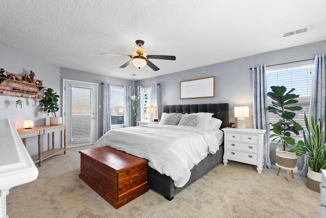 bedroom featuring access to exterior, a ceiling fan, light carpet, a textured ceiling, and visible vents