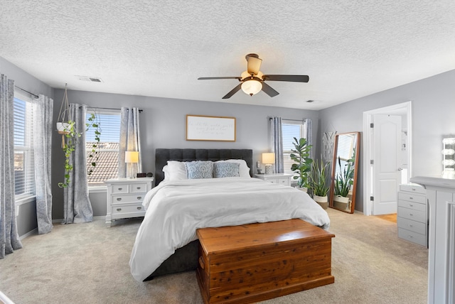 bedroom with light carpet, ceiling fan, multiple windows, and visible vents