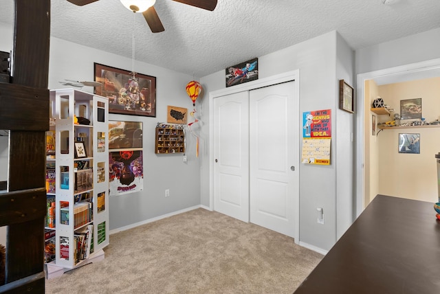 carpeted bedroom featuring ceiling fan, a textured ceiling, baseboards, and a closet