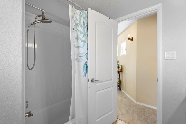 bathroom with shower / tub combo with curtain, a textured ceiling, and baseboards