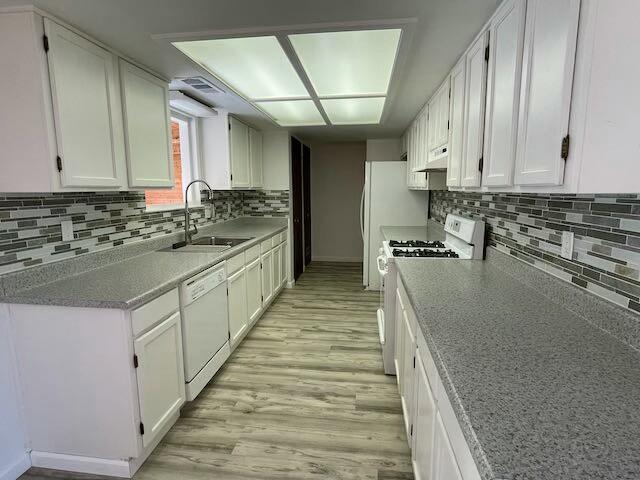 kitchen featuring white appliances, backsplash, sink, light hardwood / wood-style floors, and white cabinetry