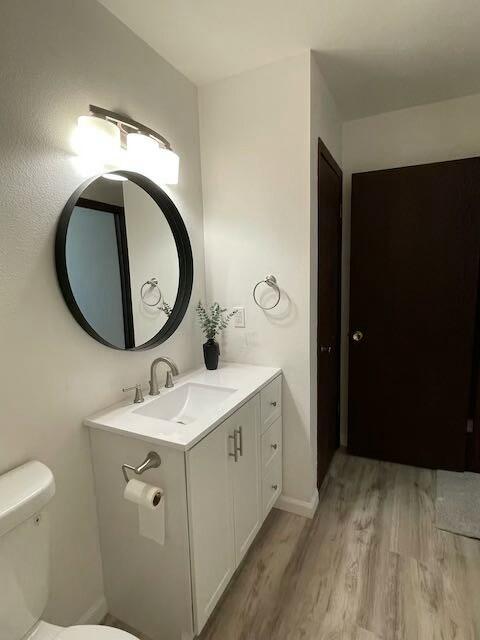 bathroom with hardwood / wood-style flooring, vanity, and toilet