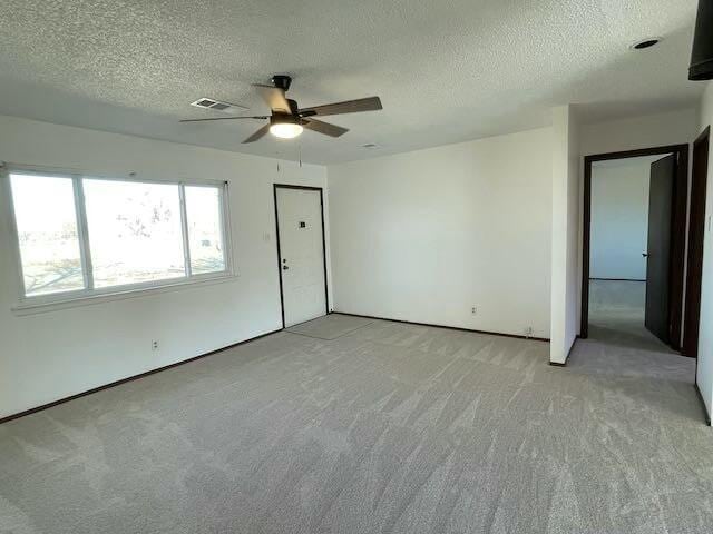 interior space with ceiling fan, light colored carpet, and a textured ceiling