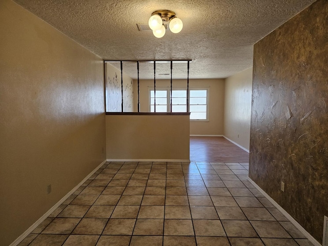 unfurnished room with a textured ceiling and tile patterned floors