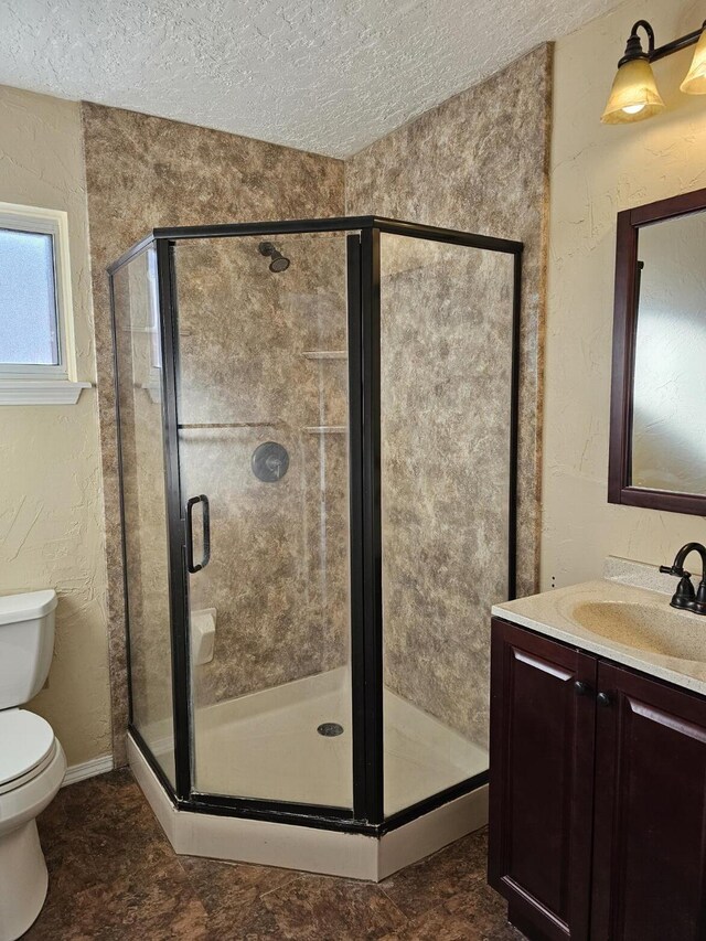 bathroom featuring a textured ceiling, an enclosed shower, vanity, and toilet