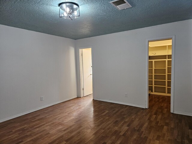 spare room featuring a textured ceiling and dark hardwood / wood-style flooring