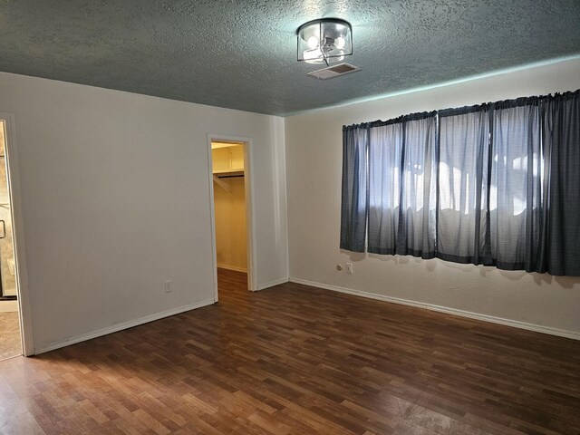 empty room with dark hardwood / wood-style flooring and a textured ceiling