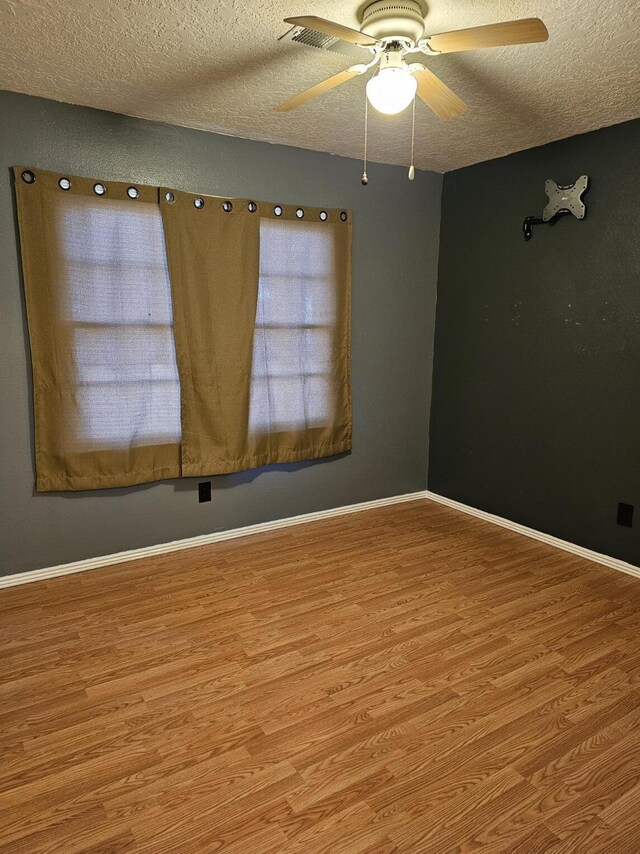 spare room with a textured ceiling, ceiling fan, and light hardwood / wood-style flooring