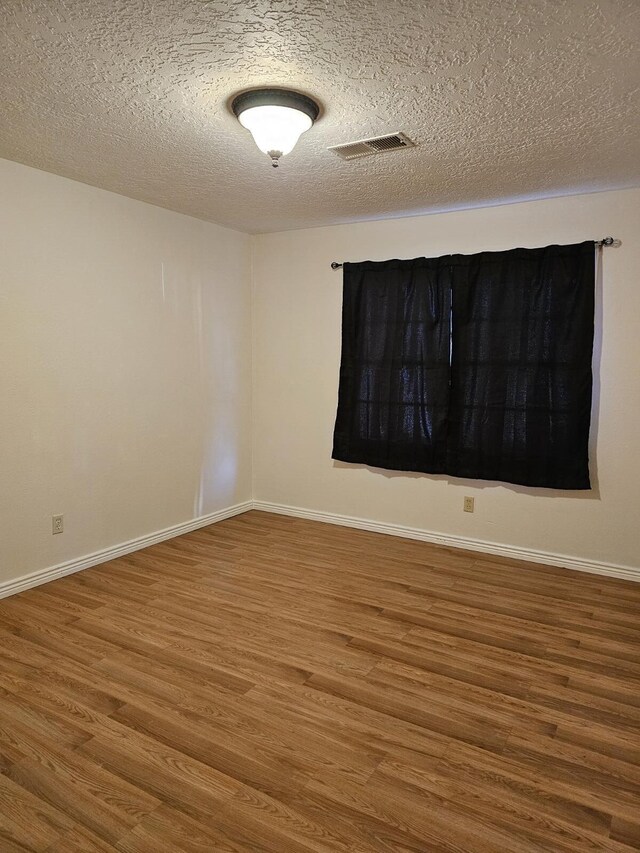 spare room with a textured ceiling and hardwood / wood-style floors