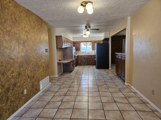 kitchen with tasteful backsplash, stainless steel refrigerator, light tile patterned flooring, ceiling fan, and sink