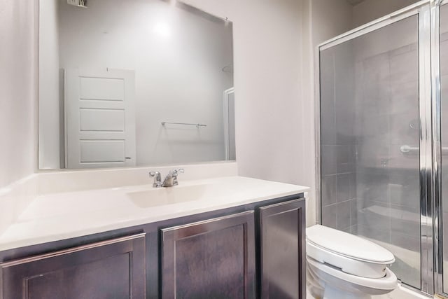 bathroom featuring vanity, toilet, and a shower with door