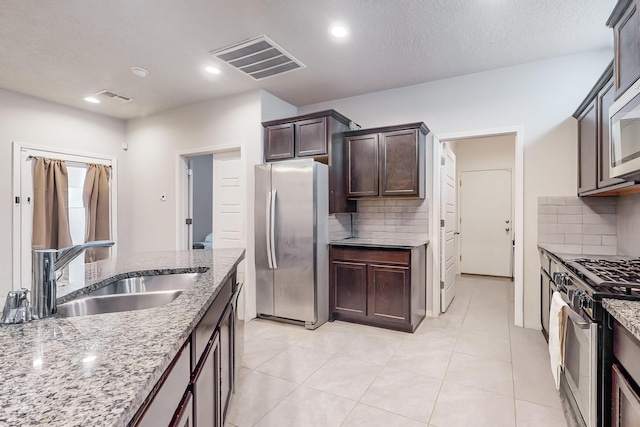 kitchen with decorative backsplash, sink, stainless steel appliances, and light stone counters