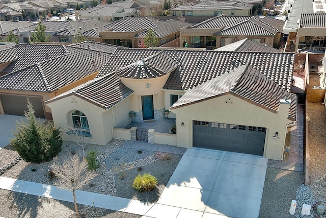 view of front of home featuring driveway, a garage, a residential view, a tiled roof, and stucco siding