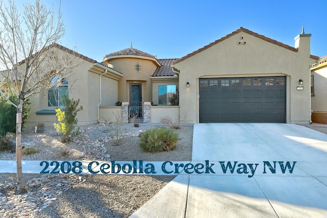 mediterranean / spanish home with a garage, driveway, a tiled roof, and stucco siding