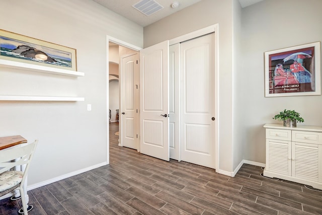 unfurnished office featuring baseboards, arched walkways, visible vents, and wood tiled floor