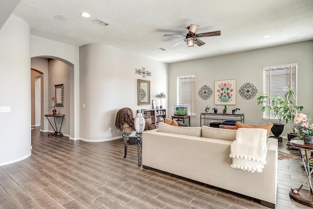 living room with arched walkways, ceiling fan, a textured ceiling, and wood finished floors