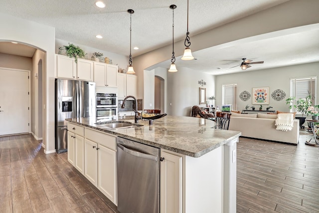 kitchen featuring wood tiled floor, arched walkways, stainless steel appliances, and a sink