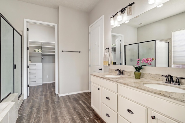 bathroom with wood tiled floor, a sink, and a shower stall