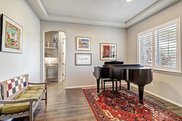 living area featuring baseboards, arched walkways, dark wood finished floors, and a textured ceiling