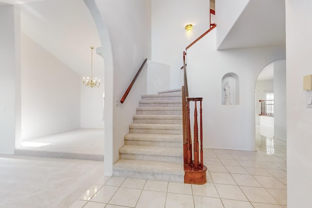 stairs with a notable chandelier and tile patterned floors