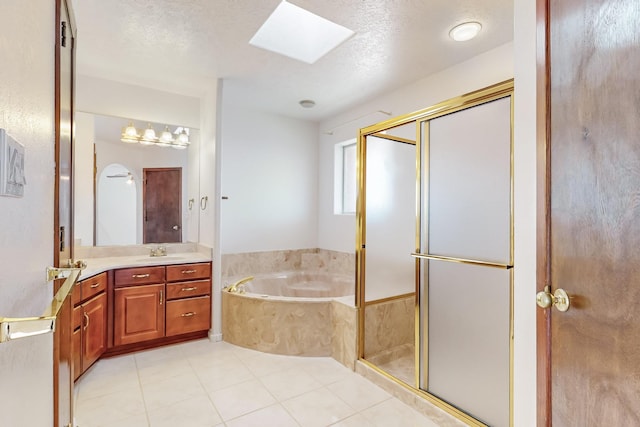 bathroom with a textured ceiling, shower with separate bathtub, tile patterned flooring, a skylight, and vanity