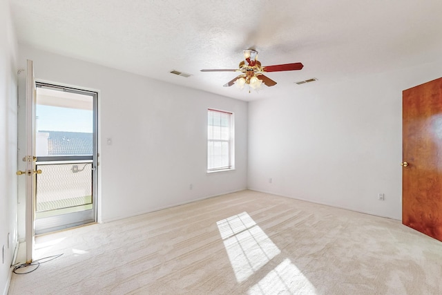 spare room with a textured ceiling, ceiling fan, and light colored carpet