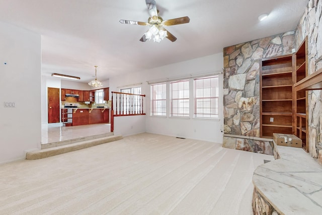 unfurnished living room featuring light colored carpet and ceiling fan with notable chandelier