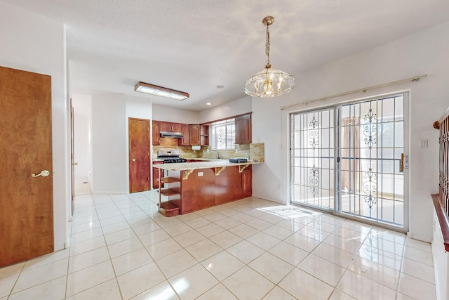 kitchen featuring an inviting chandelier, light tile patterned floors, kitchen peninsula, decorative backsplash, and pendant lighting