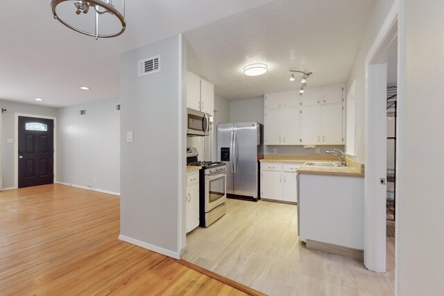 kitchen featuring visible vents, a sink, stainless steel appliances, light countertops, and light wood-style floors