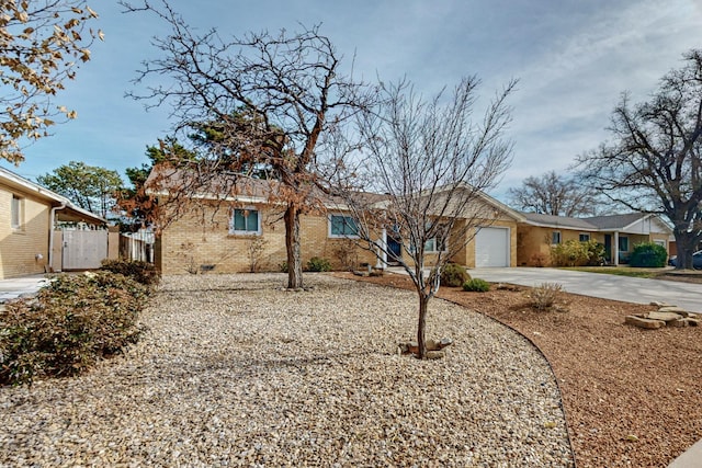 ranch-style home with brick siding, an attached garage, driveway, and fence