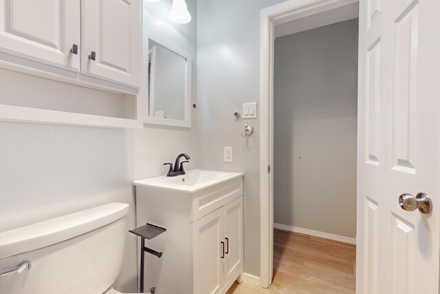 bathroom with baseboards, toilet, wood finished floors, and vanity