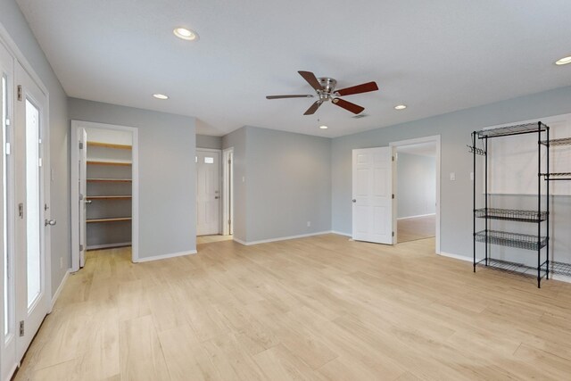 unfurnished bedroom with recessed lighting, a walk in closet, baseboards, and light wood-style floors