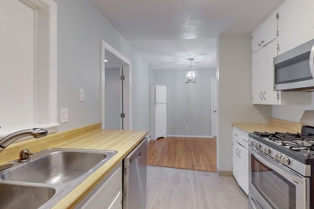 kitchen featuring a sink, light countertops, white cabinets, light wood-style floors, and appliances with stainless steel finishes