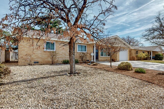 ranch-style home with an attached garage, brick siding, driveway, and crawl space