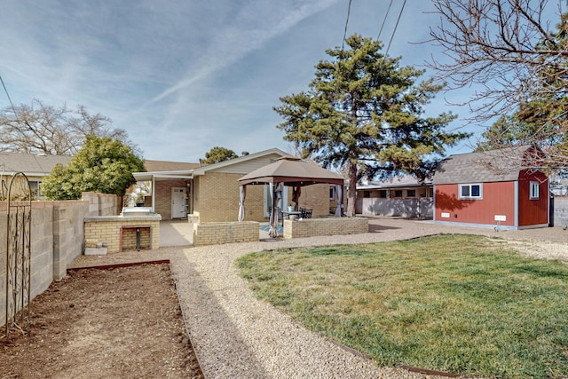 exterior space with a lawn, a patio, fence, a gazebo, and brick siding