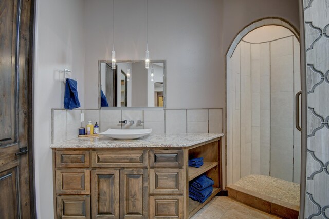 bedroom with a tray ceiling, access to exterior, a stone fireplace, and ensuite bath