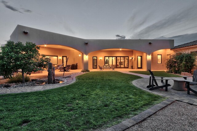 back of house with a patio, a lawn, and stucco siding