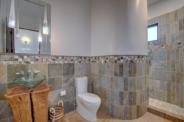 full bath featuring toilet, a wainscoted wall, tile patterned flooring, and tile walls