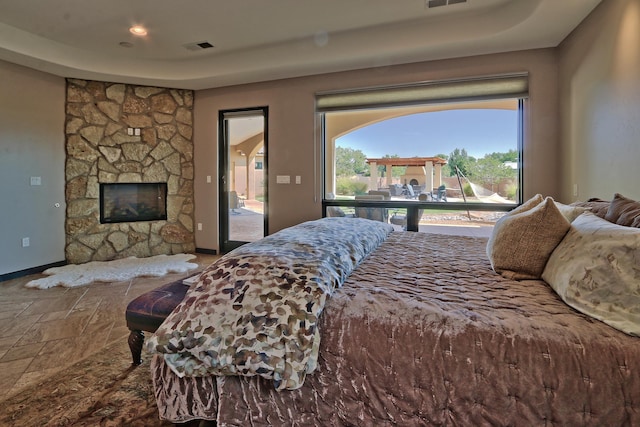 bedroom featuring a stone fireplace and access to exterior