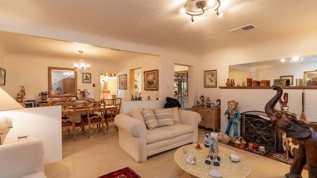 carpeted living room with a textured ceiling, a brick fireplace, and a notable chandelier