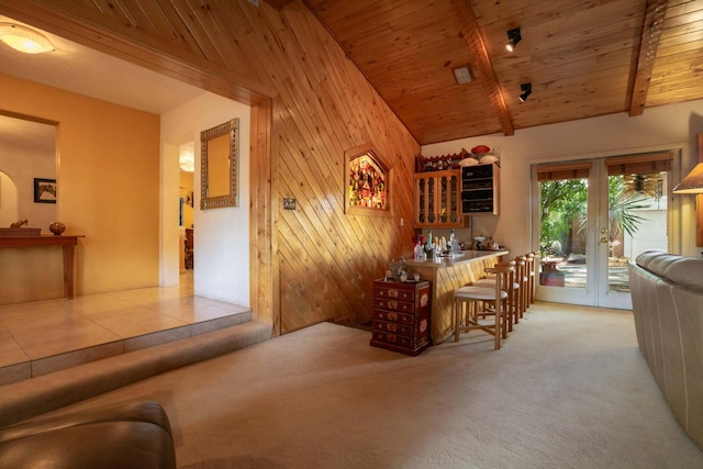 carpeted dining area featuring bar, high vaulted ceiling, wooden ceiling, wooden walls, and beam ceiling