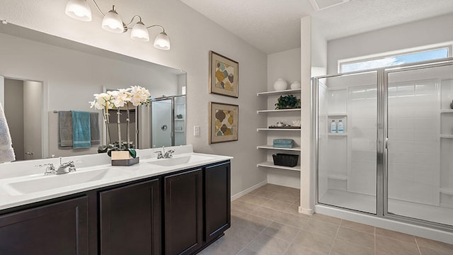 bathroom featuring tile patterned flooring, vanity, a textured ceiling, and walk in shower