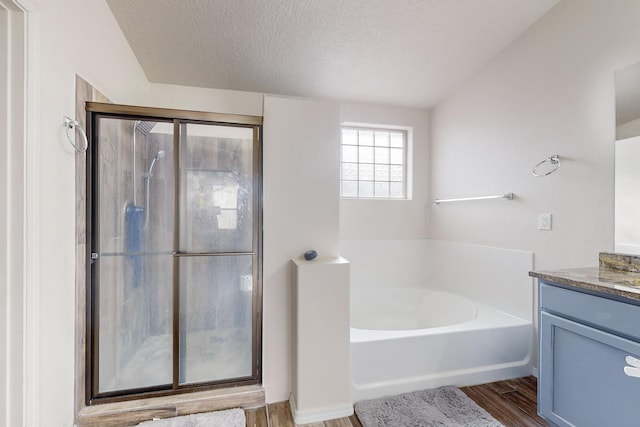 bathroom featuring hardwood / wood-style flooring, vanity, shower with separate bathtub, and a textured ceiling