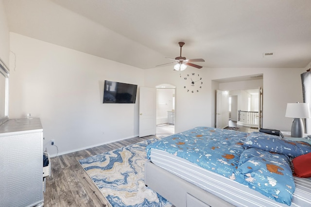 bedroom featuring hardwood / wood-style flooring, ceiling fan, lofted ceiling, and connected bathroom