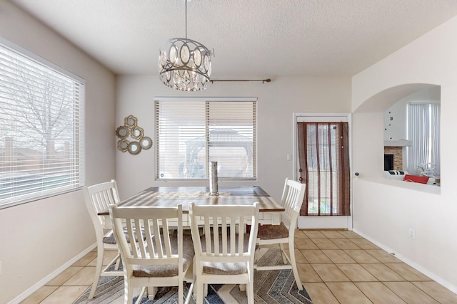 tiled dining area with plenty of natural light, a textured ceiling, and an inviting chandelier