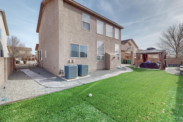 rear view of property featuring a gazebo, central air condition unit, and a yard