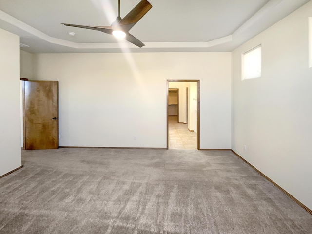 carpeted empty room featuring a raised ceiling and ceiling fan