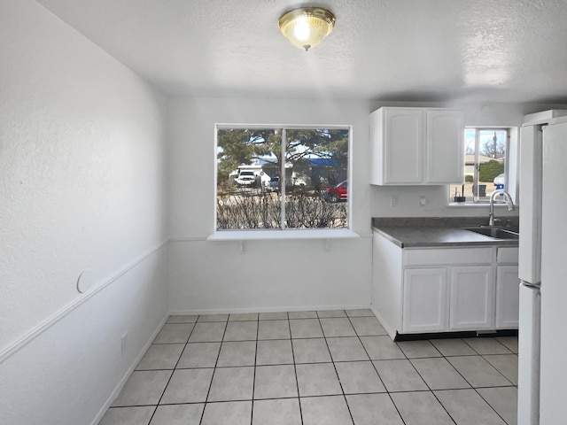 kitchen with white cabinetry, sink, white refrigerator, a textured ceiling, and light tile patterned floors