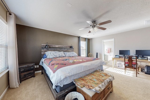 carpeted bedroom featuring ensuite bath, ceiling fan, and a textured ceiling