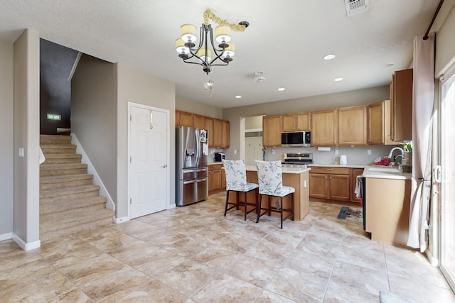 kitchen with sink, appliances with stainless steel finishes, a notable chandelier, a kitchen island, and a breakfast bar area